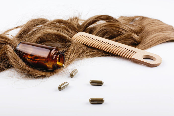 Hair care supplements with wooden comb on brown hair.